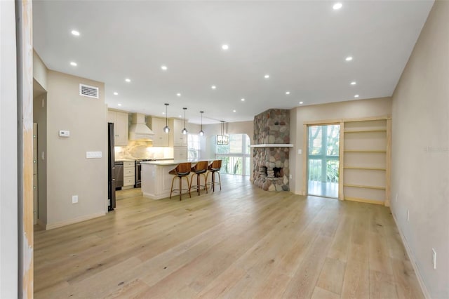 living room with a stone fireplace and light wood-type flooring