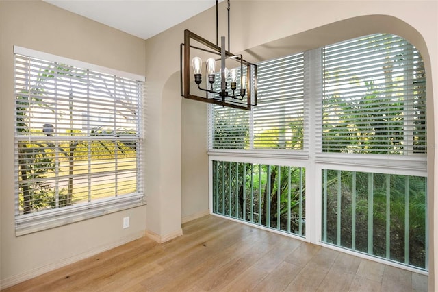 unfurnished dining area featuring a chandelier and light wood-type flooring