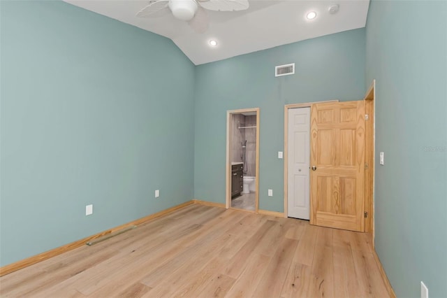 unfurnished bedroom featuring ensuite bath, vaulted ceiling, ceiling fan, and light wood-type flooring