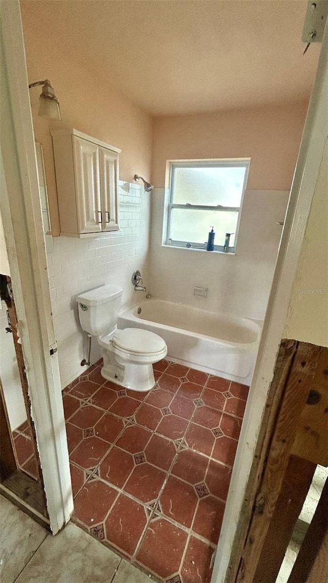 bathroom featuring tile walls, bathing tub / shower combination, and toilet