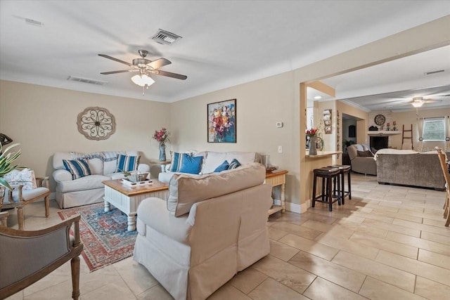 living room featuring ceiling fan, ornamental molding, and a fireplace