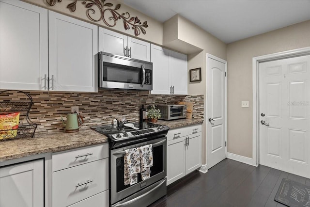 kitchen with appliances with stainless steel finishes, white cabinets, light stone counters, and decorative backsplash