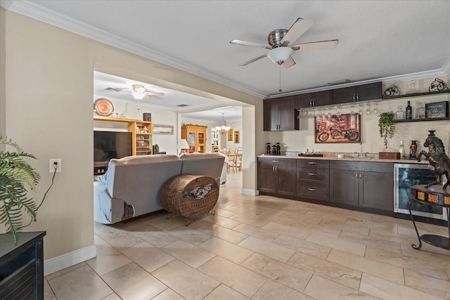 bar with ceiling fan with notable chandelier, sink, beverage cooler, dark brown cabinetry, and crown molding