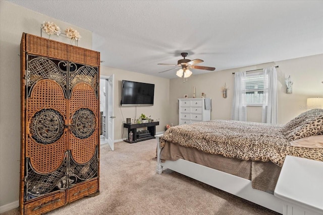 carpeted bedroom featuring ceiling fan and a textured ceiling