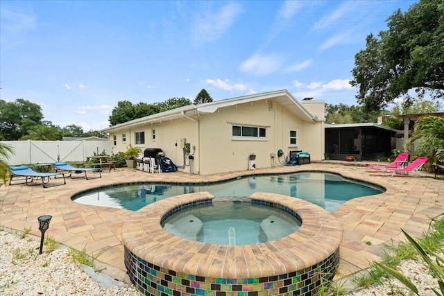 view of swimming pool with an in ground hot tub, a sunroom, and a patio area