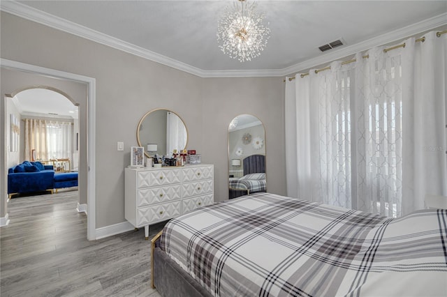 bedroom featuring arched walkways, visible vents, light wood finished floors, and crown molding