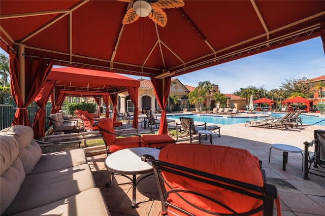 view of patio / terrace with a gazebo, a community pool, and fence