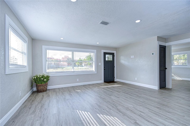 interior space with a healthy amount of sunlight, hardwood / wood-style floors, and a textured ceiling