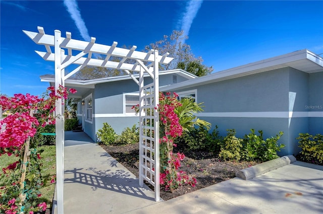 view of side of home with a pergola and stucco siding