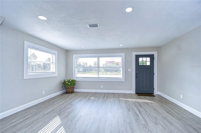 entrance foyer featuring baseboards, visible vents, a wealth of natural light, and wood finished floors