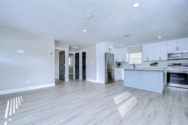 kitchen with light wood-style floors, stainless steel appliances, and backsplash