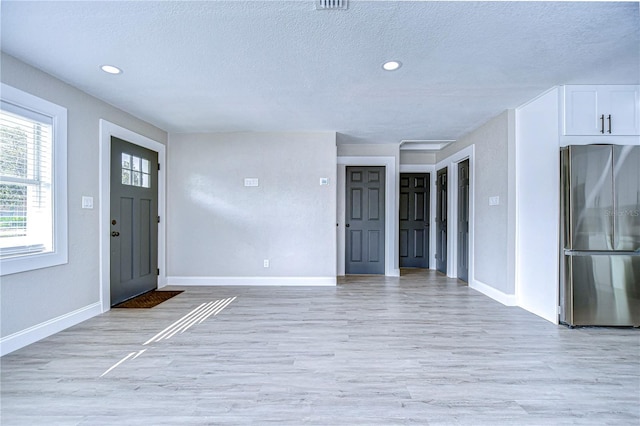 entryway featuring light wood finished floors, baseboards, a textured ceiling, and recessed lighting