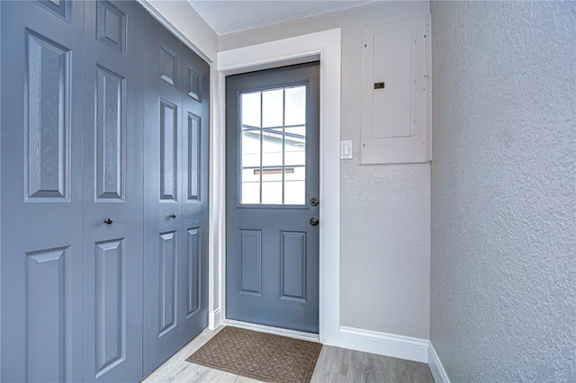 entryway featuring a textured wall, wood finished floors, and electric panel