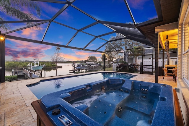 pool at dusk featuring a dock, a patio area, an outdoor hot tub, and a water view