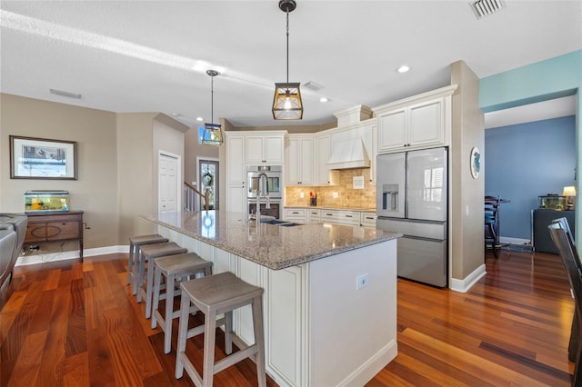 1881 Riveredge Dr, Tarpon Springs, FL 34689 - kitchen featuring stainless steel appliances, tasteful backsplash, dark wood-style flooring, custom range hood, and light stone counters