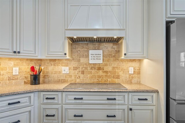 1881 Riveredge Dr, Tarpon Springs, FL 34689 - kitchen featuring premium range hood, black electric stovetop, white cabinetry, decorative backsplash, and fridge