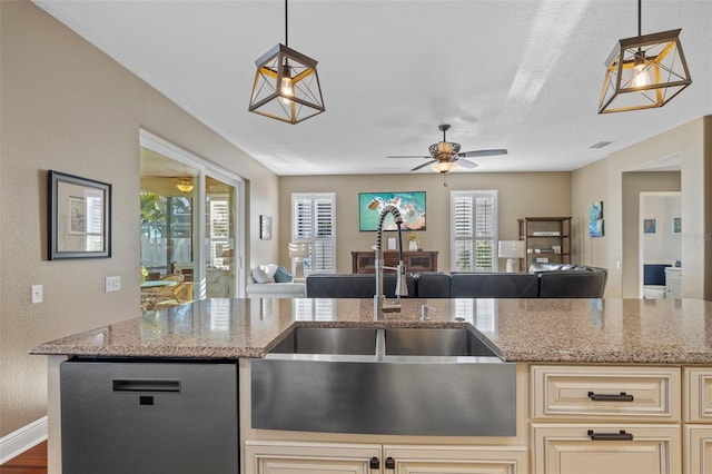 1881 Riveredge Dr, Tarpon Springs, FL 34689 - kitchen with cream cabinets, a sink, open floor plan, a ceiling fan, and light stone counters