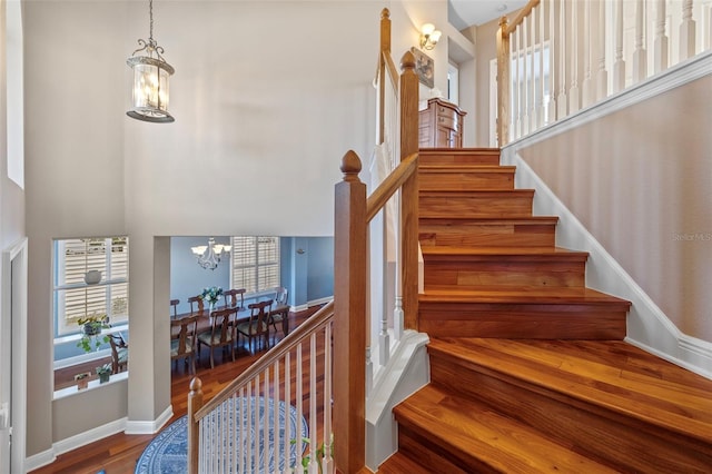 1881 Riveredge Dr, Tarpon Springs, FL 34689 - stairway with a chandelier, wood finished floors, a towering ceiling, and baseboards