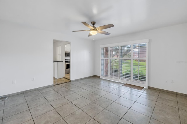 tiled spare room with ceiling fan