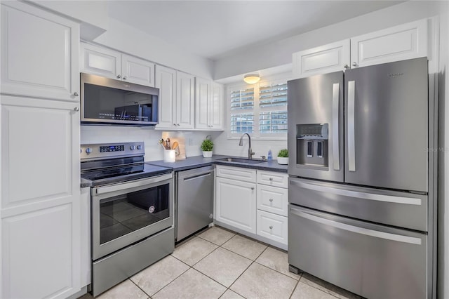 kitchen with sink, tasteful backsplash, light tile patterned floors, stainless steel appliances, and white cabinets