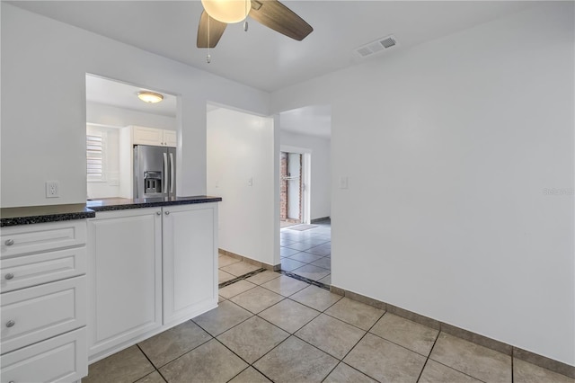 kitchen with stainless steel refrigerator with ice dispenser, white cabinetry, ceiling fan, and light tile patterned floors