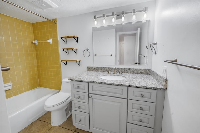 full bathroom featuring tile patterned floors, toilet, tiled shower / bath, a textured ceiling, and vanity