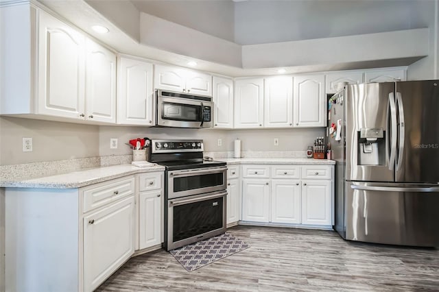 kitchen with white cabinetry, light stone countertops, light hardwood / wood-style flooring, and stainless steel appliances