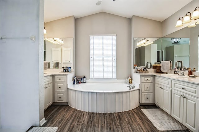 bathroom with hardwood / wood-style flooring, a tub to relax in, vanity, and vaulted ceiling