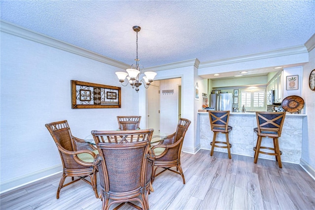 dining area with ornamental molding, a textured ceiling, and light wood-type flooring