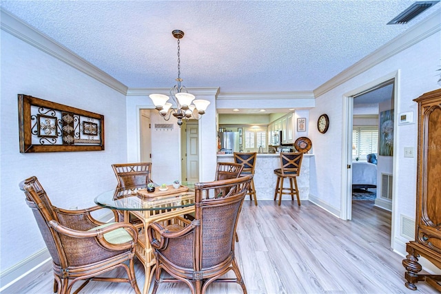 dining area featuring crown molding, a textured ceiling, light hardwood / wood-style floors, and a chandelier