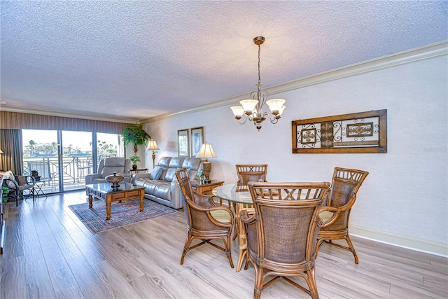 dining space featuring an inviting chandelier, crown molding, light hardwood / wood-style floors, and a textured ceiling