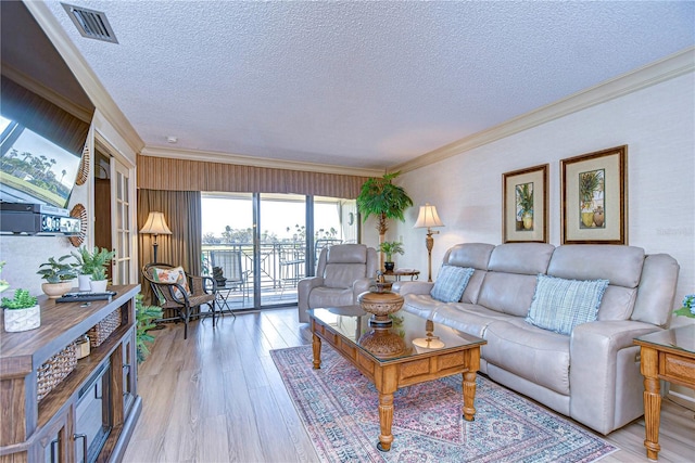 living room featuring ornamental molding, light hardwood / wood-style floors, and a textured ceiling