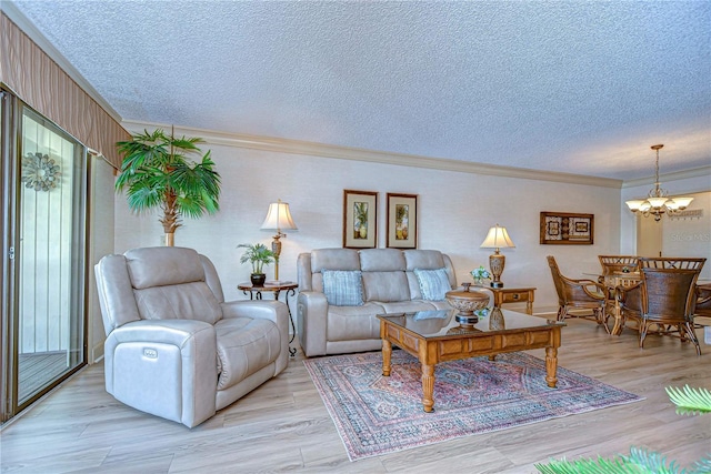 living room with an inviting chandelier, ornamental molding, light hardwood / wood-style floors, and a textured ceiling