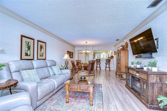 living room featuring an inviting chandelier, crown molding, light hardwood / wood-style flooring, and a textured ceiling