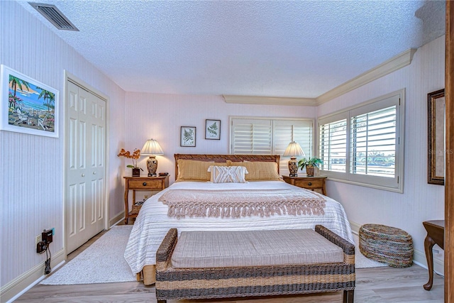 bedroom featuring a textured ceiling, light wood-type flooring, and a closet