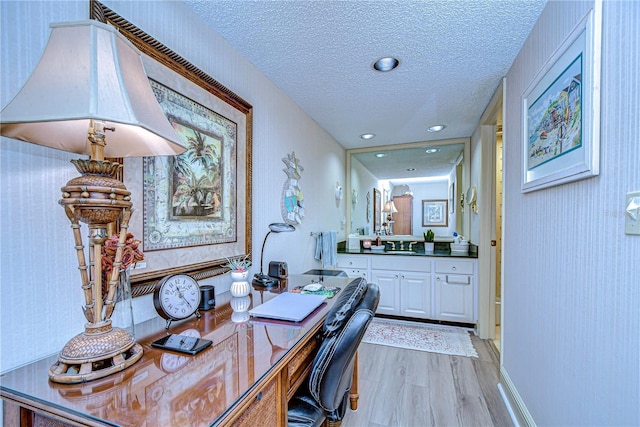 office with sink, light hardwood / wood-style floors, and a textured ceiling