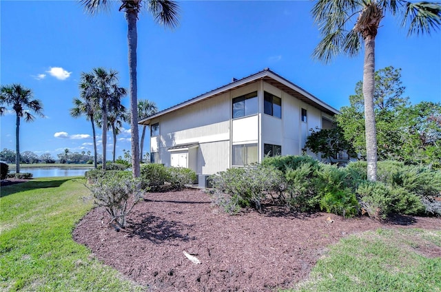 view of side of property featuring a water view, a yard, and central AC