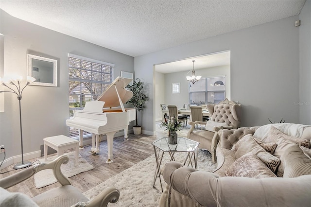 living room with a notable chandelier, a textured ceiling, and light wood-type flooring