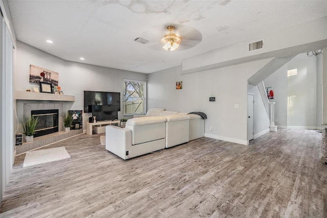 living room featuring ceiling fan, a fireplace, and light hardwood / wood-style floors