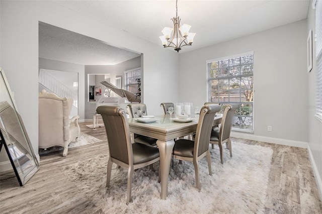 dining room featuring an inviting chandelier, light hardwood / wood-style floors, and a textured ceiling