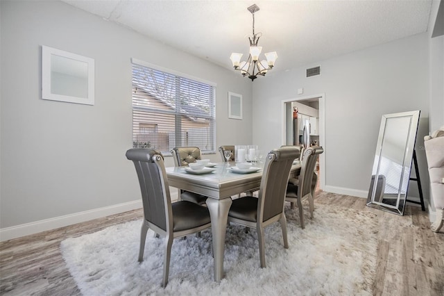 dining area with an inviting chandelier and light hardwood / wood-style floors