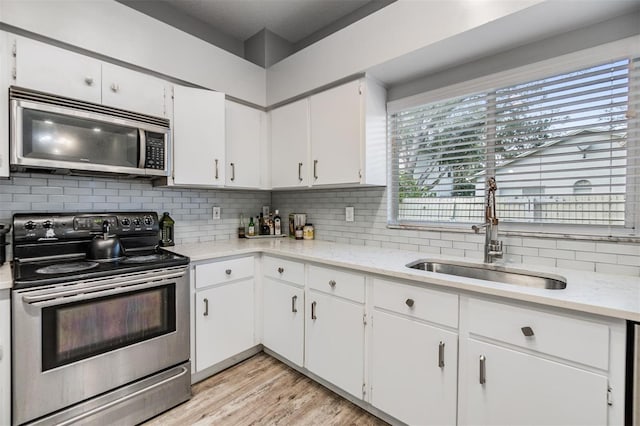 kitchen featuring tasteful backsplash, sink, white cabinets, and appliances with stainless steel finishes