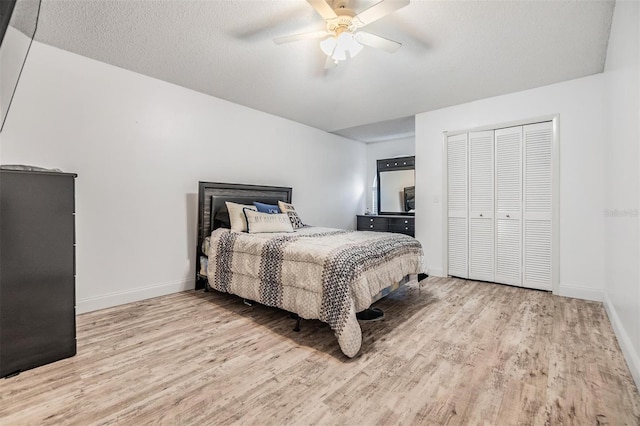 bedroom with ceiling fan, light hardwood / wood-style flooring, a closet, and a textured ceiling