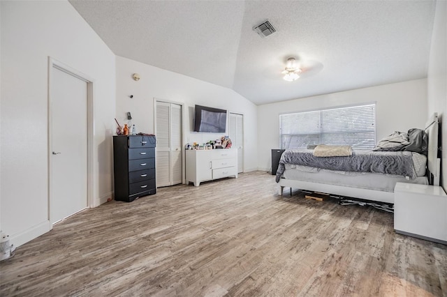 bedroom featuring wood-type flooring, lofted ceiling, and a textured ceiling