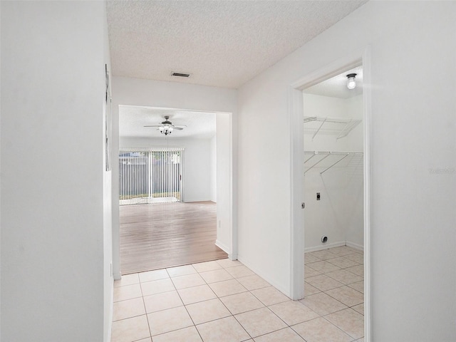 corridor with light tile patterned flooring and a textured ceiling