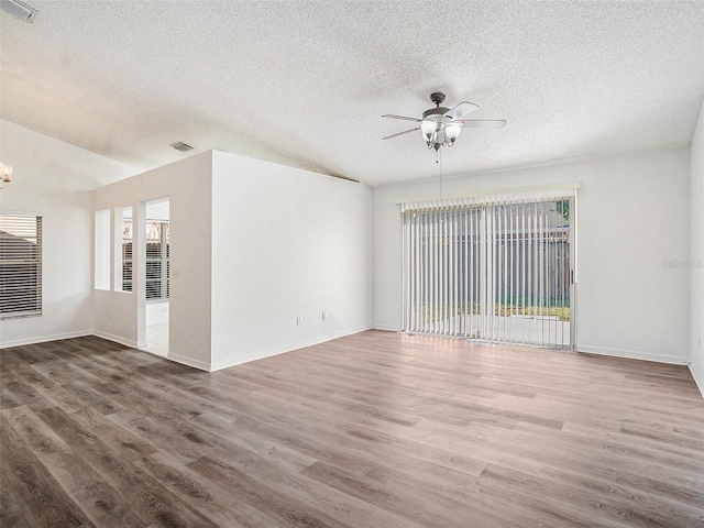 spare room featuring wood-type flooring, ceiling fan with notable chandelier, and a textured ceiling