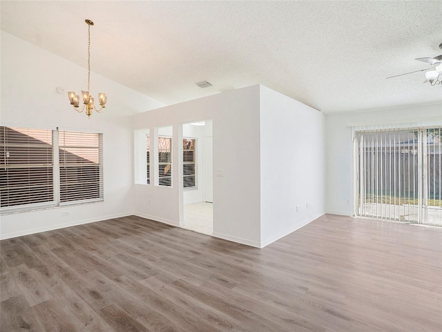 spare room with hardwood / wood-style flooring, ceiling fan with notable chandelier, a textured ceiling, and vaulted ceiling