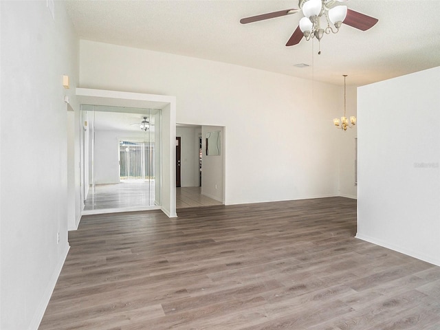 empty room with ceiling fan with notable chandelier and hardwood / wood-style floors