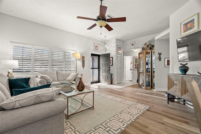 living room with ceiling fan, light hardwood / wood-style floors, and a textured ceiling