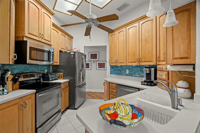 kitchen with appliances with stainless steel finishes, tasteful backsplash, hanging light fixtures, light tile patterned floors, and ceiling fan